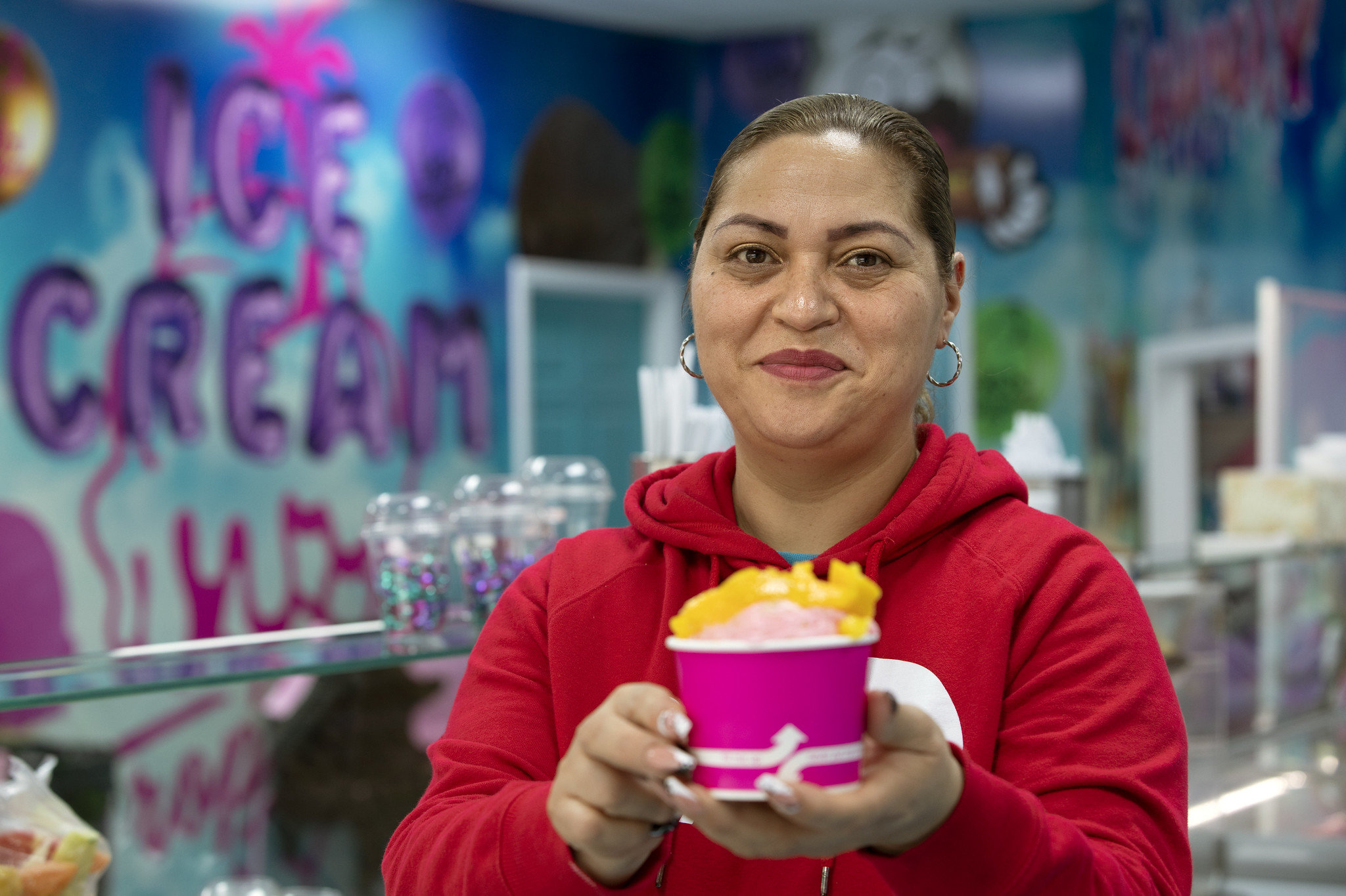 A woman smiles holding a bright pink and yellow ice cream