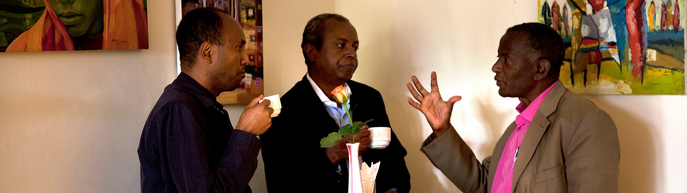 Three men talking and drinking coffee and tea
