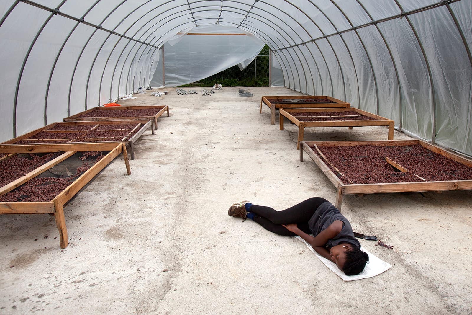 A woman napping on the floor of a room with pots of soil.