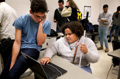 Two people working at a computer together.