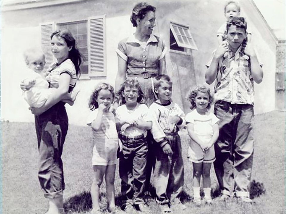 Black and white photo of a mother and eight children ranging from teenager to infant.