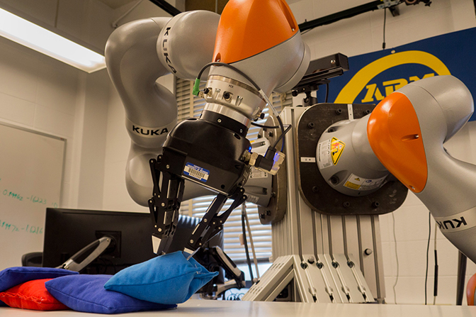 image of autonomous robotic arm delicately transferring the beanbag from a pile of objects