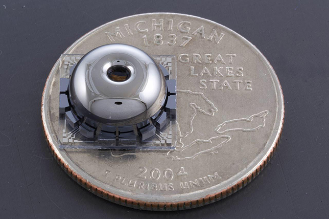 a close up image of the resonator and electrodes placed on top of a quarter for scale comparison