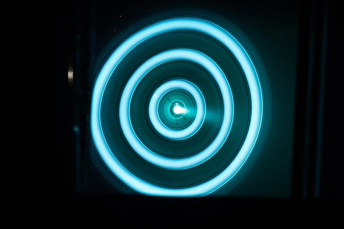 a head-on image of the thruster for mars mission firing at 50 kilowatts viewed through a warped mirror in the vacuum chamber