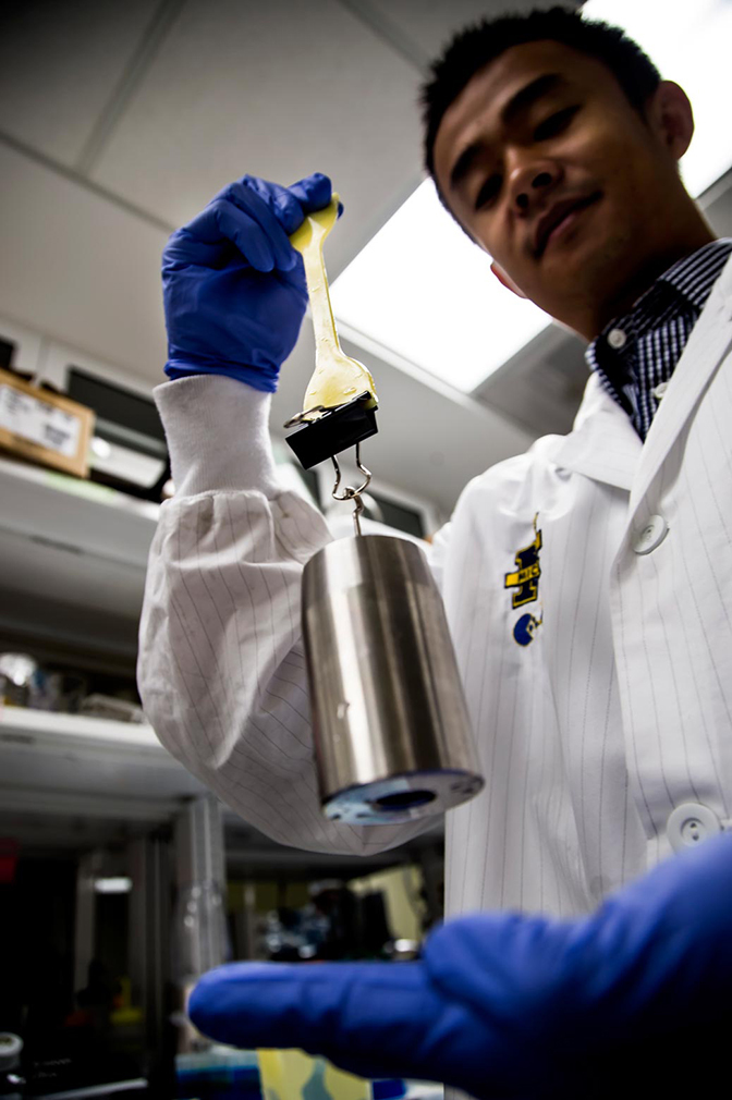 an image of research fellow lizhi xu demonstrating the tear resistance of the artificial cartilage under stress through added weights