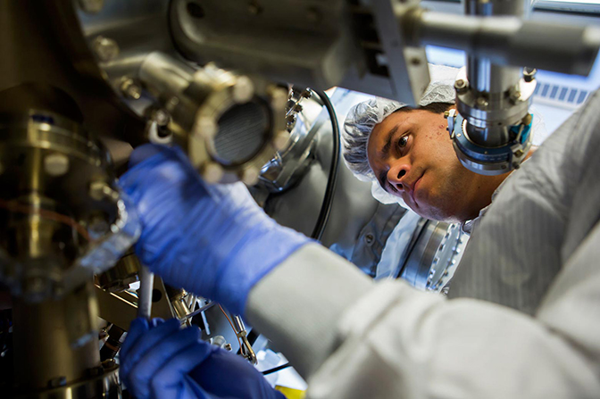 a close up image of a phd student jordan occena calibrating the molecular beam epitaxy apparatus