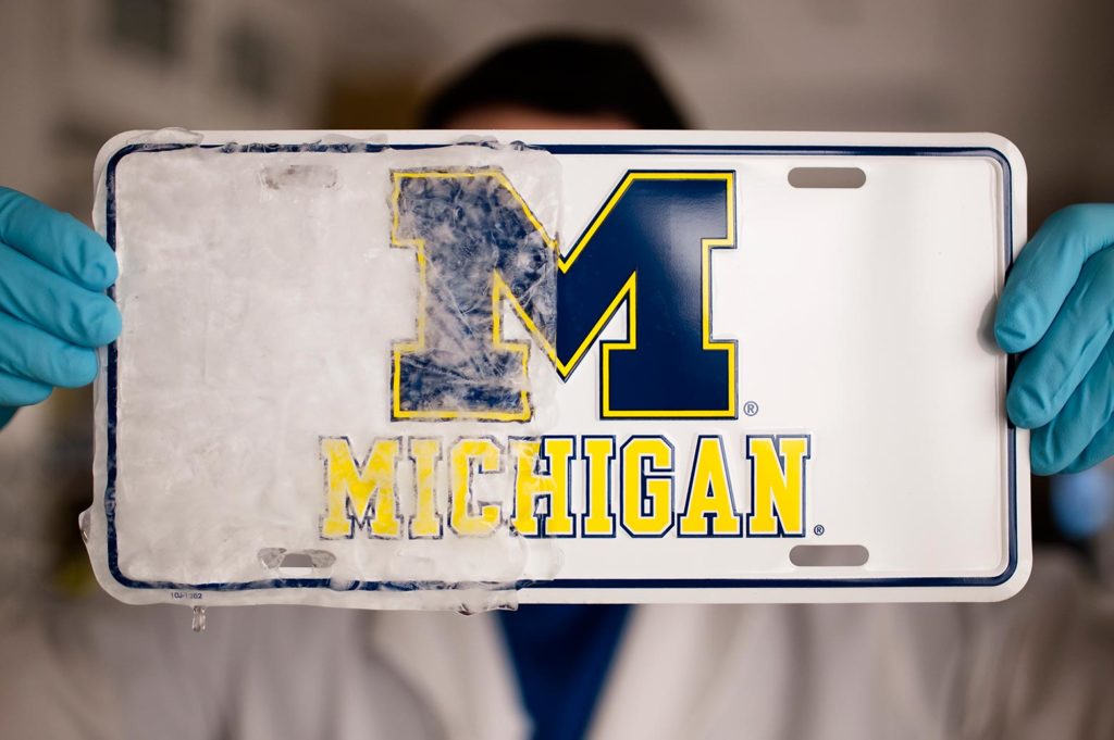 Person holding up a license plate with the icephobic coating applied