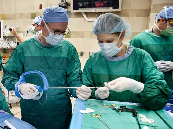 two surgeons in scrubs hold flexdex device