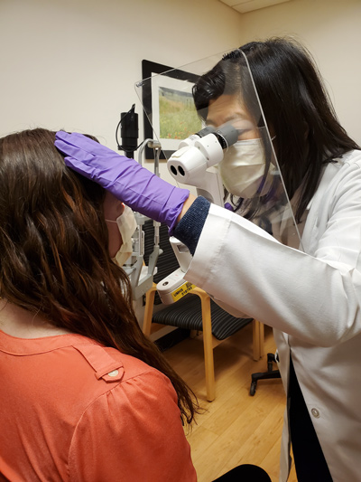 Doctor looks at patient's eyes through a shield designed to provide protection from COVID 20