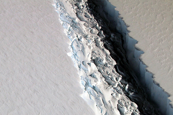 An aerial view of a large canyon and neighboring mountains on an iceberg.