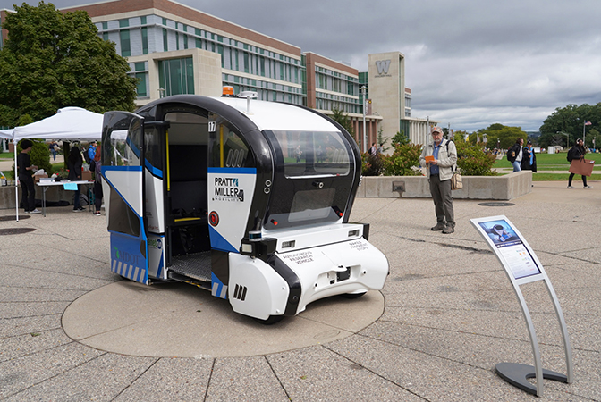 A small blue and white vehicle with an open door that extends from the ground to the top of the vehicle.