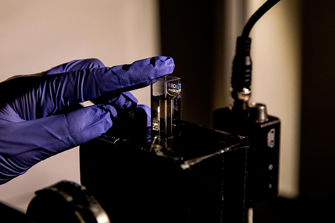 a close up image of a phd student applying a gel made up of chiromagnetic nanoparticles that are a conduit for modulating light to a laser apparatus