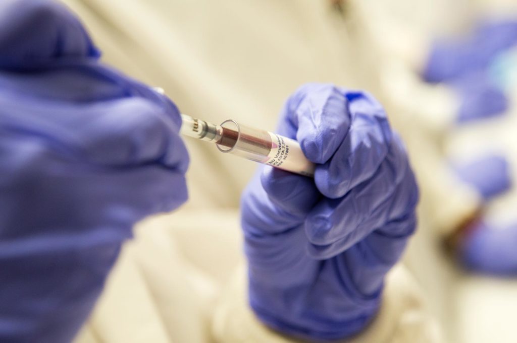 A person pipetting blood into a vial.