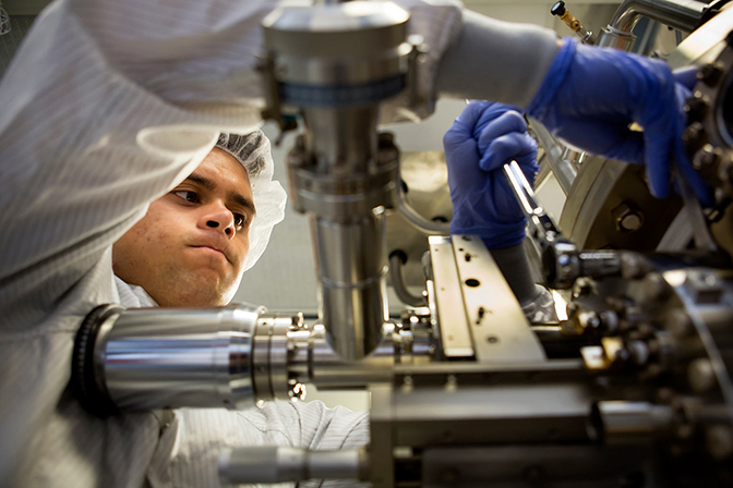 A researcher adjusts metal parts of a large machine.