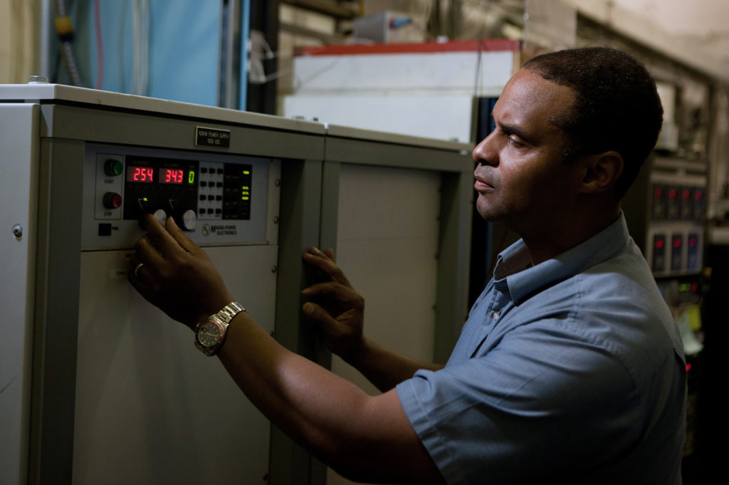 A man adjusting knobs on a large machine.