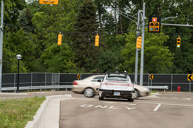 A car speeding through an intersection while a second car is stopped at the light.