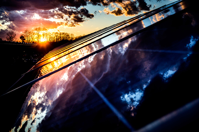 an image of solar array on UM North campus with reflection of a sunset on the solar cells