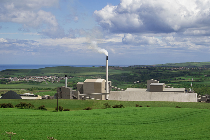 A factory in the distance among green fields.