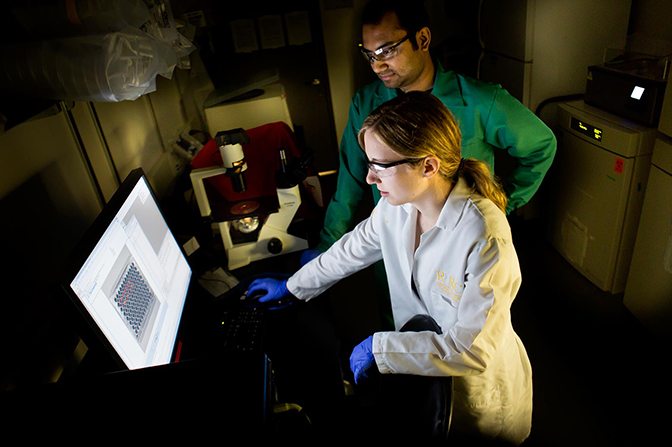 Image of Grace Bushnell and Shreyas Rao looking at screen for results in a lab