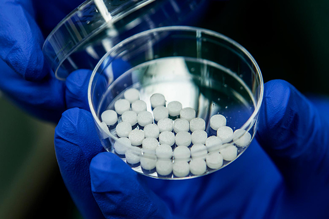 A close up image of Shreyas Rao holding a petri dish containing cancer-attracting devices