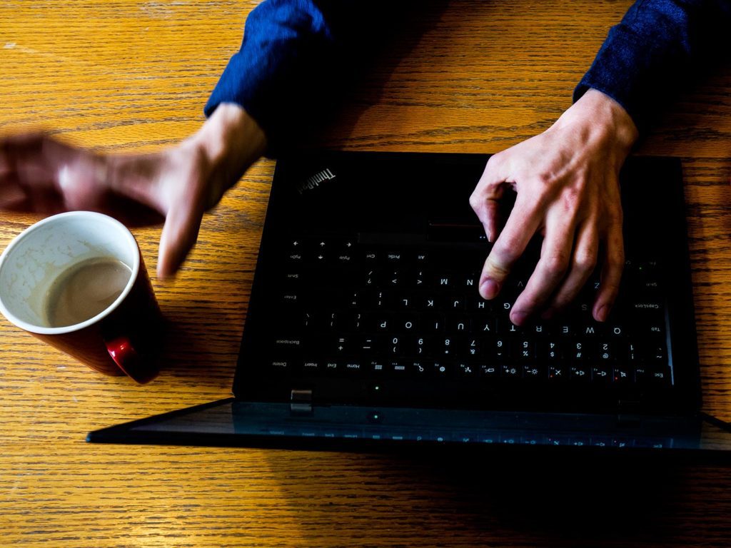 An overhead view of a laptop with a cup of coffee beside it.