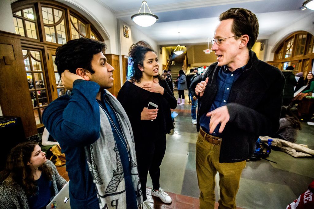 Halderman talking to two students inside the Michigan Union.