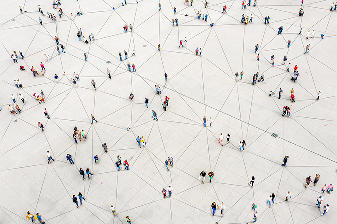 An aerial view of many people connected by a network of lines on the floor.