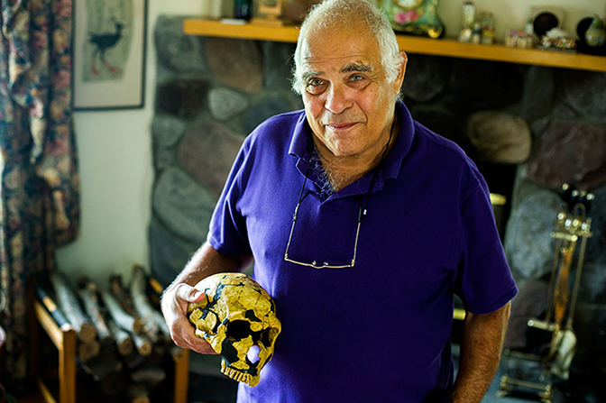 A man holding a model of a skull.