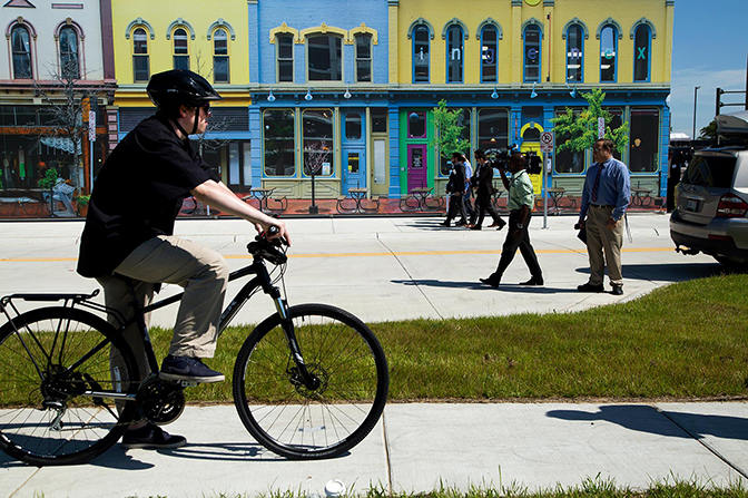 A street view of the MCity with people walking and on a bike