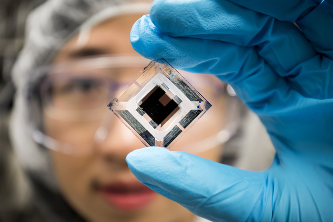 Xiaozhou Che, EECS Graduate Research Assistant, holds an organic tandem photovoltaic cell.