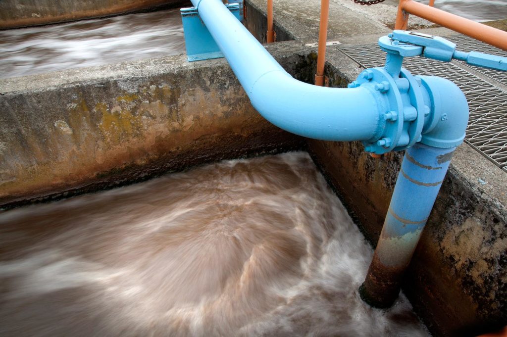 Brown wastewater rushing through blue pipes.