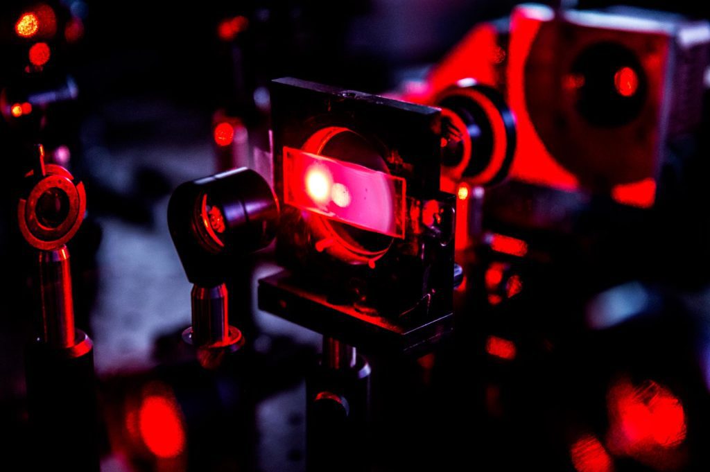 A device holding a slide of glass and shining a red laser at it.