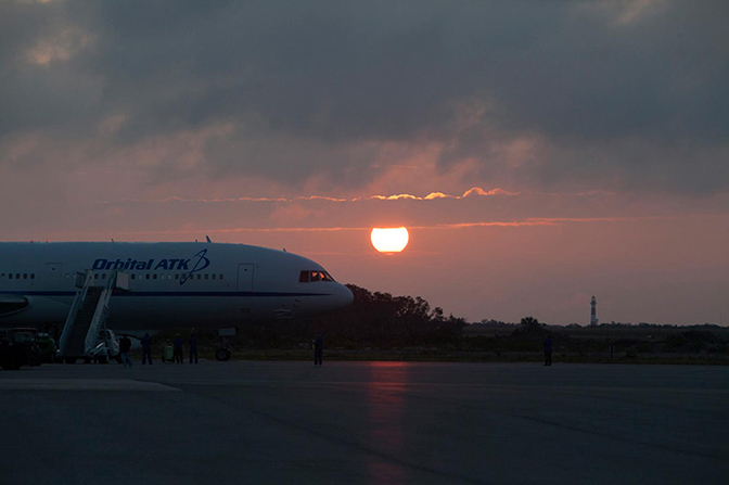 A plane on the ground with a sunset in the background.