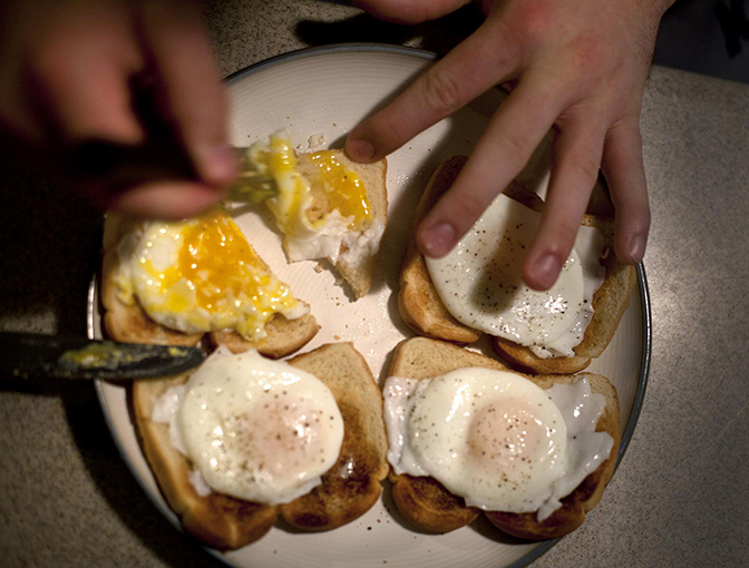 Four pieces of toast with eggs on top.