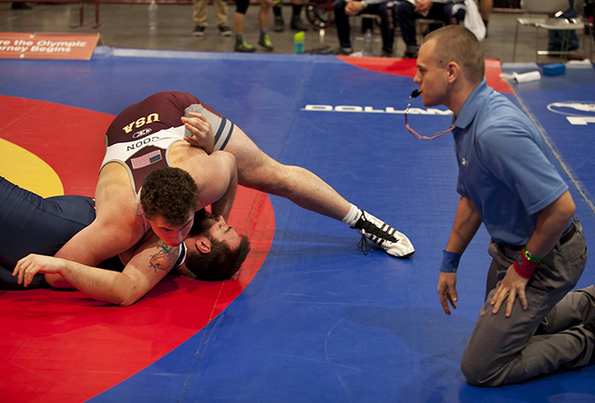 Two people wrestling on a mat.