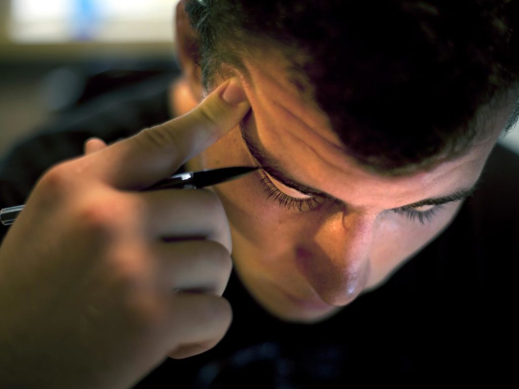 A person with their finger pressed to their temple, holding a pencil and thinking.