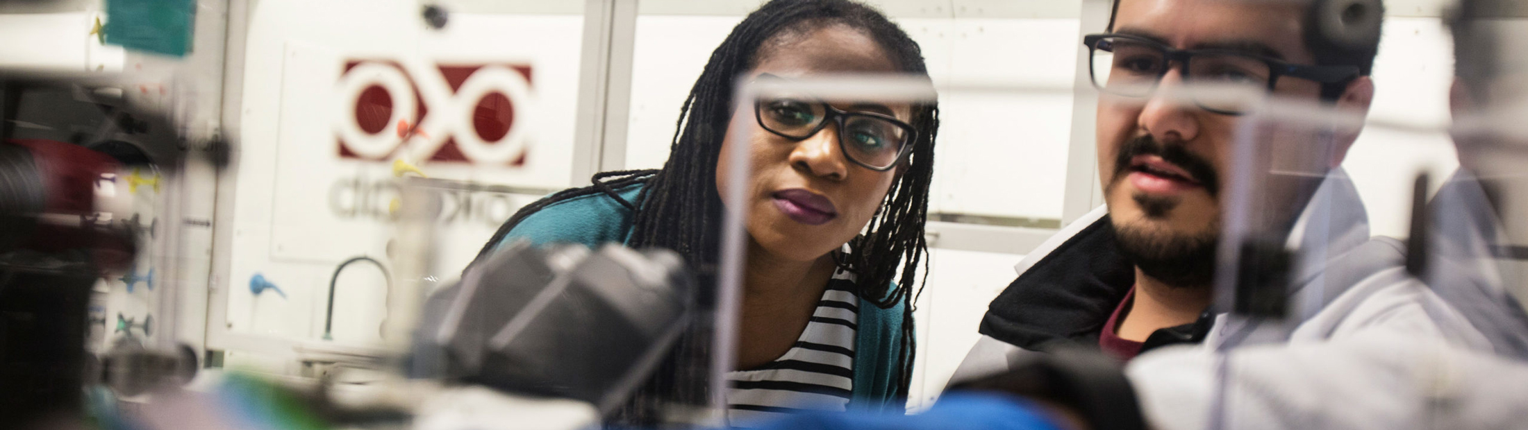 Mario Gutierrez consults Prof. Lola Eniola while using fluorescent microscopy to study the effect of red blood rigidification on the thermodynamics of blood flow.