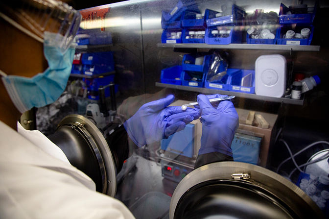 Image of Michael Wang using a glove box to inspect a lithium metal battery cell in a lab