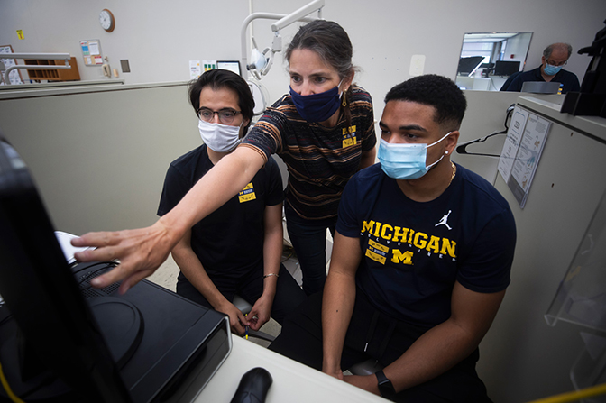 Image of Michigan Engineering researchers examining aerosolization data in their lab