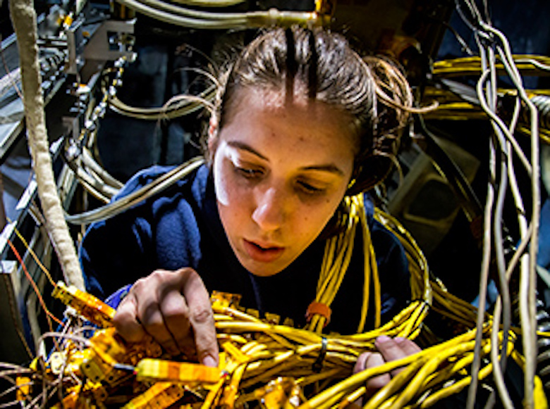 Sarah Cusson, AERO PhD student, checks on the X3 thruster after a test run in the Plasmadynamics & Electric Propulsion Laboratory.