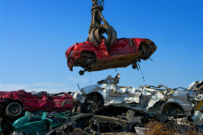 A car is lifted in a junkyard