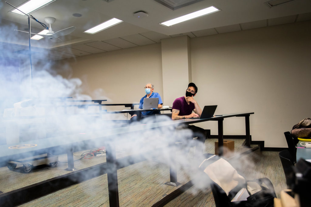 Jesse Capecelatro and Andre Boehman observe a smoke machine as part of their experiment to study how particles move through a classroom. Photo: Robert Coelius/Michigan Engineering