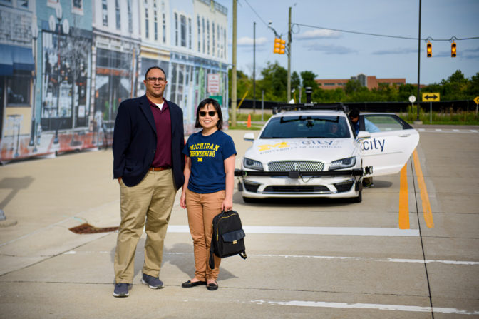 Lionel Robert, associate professor of information, and X. Jessie Yang, assistant professor of industrial and operations engineering, stand in front of an autonomous vehicle at Mcity, an autonomous vehicle testing ground. Photo: Jeffrey M. Smith/School of Information.