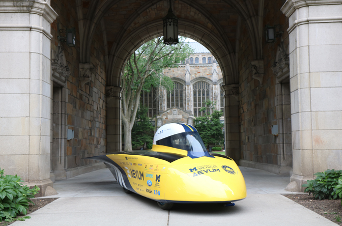 The Aevum solar car sitting on pavement under the archway of the Law Quad