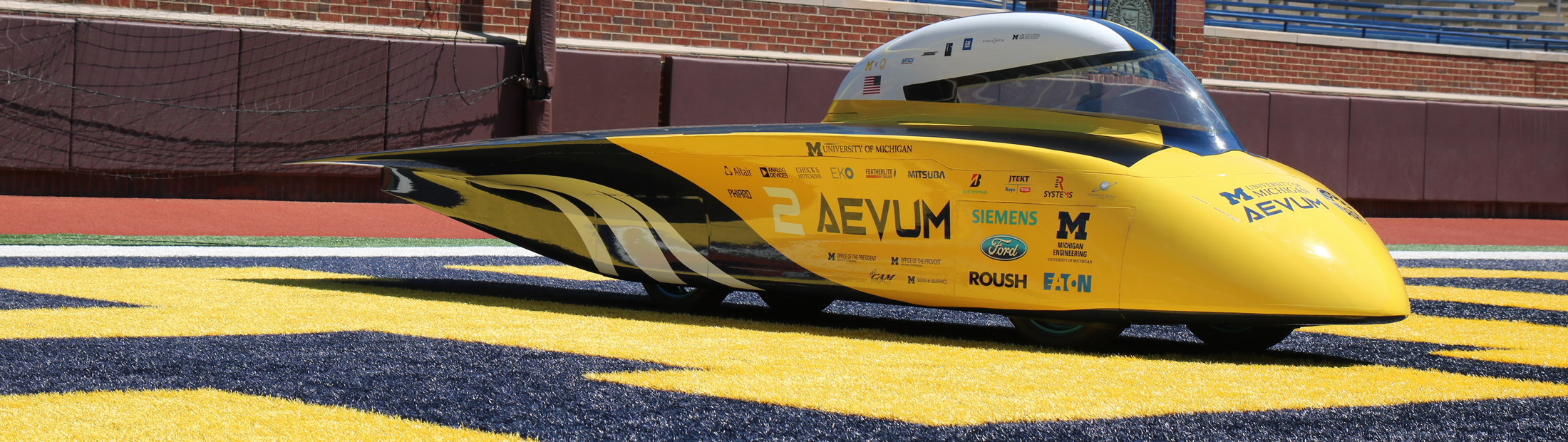 The Aevum solar car sitting in the end zone of the Big House on a sunny day