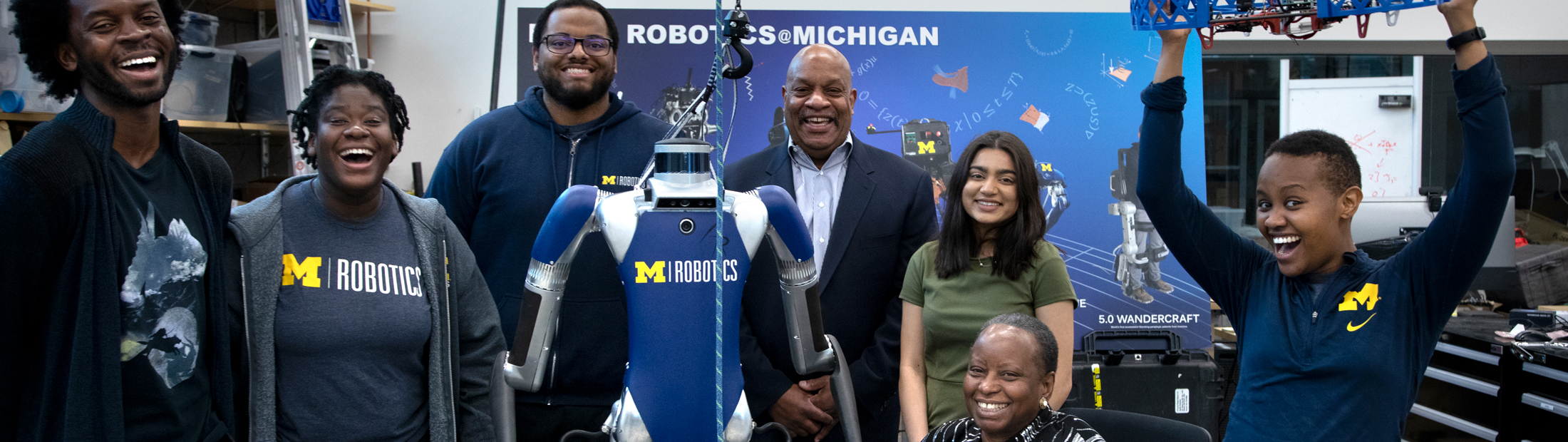 The McNeils in a robotics lab with graduate students posing together