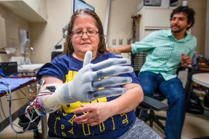Karen Sussex, an upper-limb amputee from Jackson, Mich., operates a Touch Bionics I-LIMB prosthetic hand as Alex Vaskov, robotics Ph.D. candidate, looks on during a testing session at a lab in the University of Michigan Hospital in Ann Arbor. Photo: Robert Coelius/Michigan Engineering