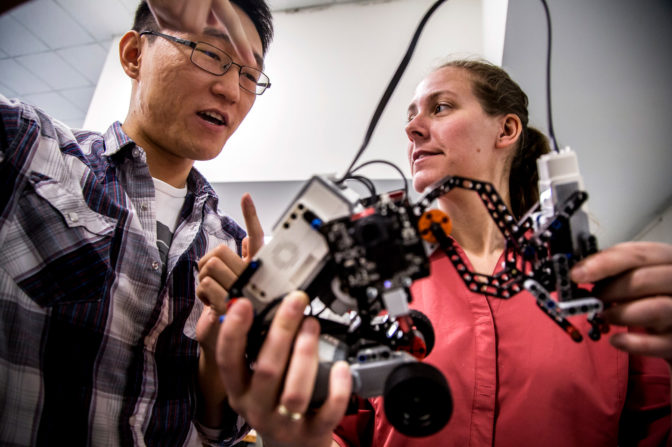 Ding Zhang, ME PhD Student, and Kira Barton, associate professor of mechanical engineering, discuss results from a recent test of a robot that uses cooperative algorithms. Photo: Joseph Xu/Michigan Engineering