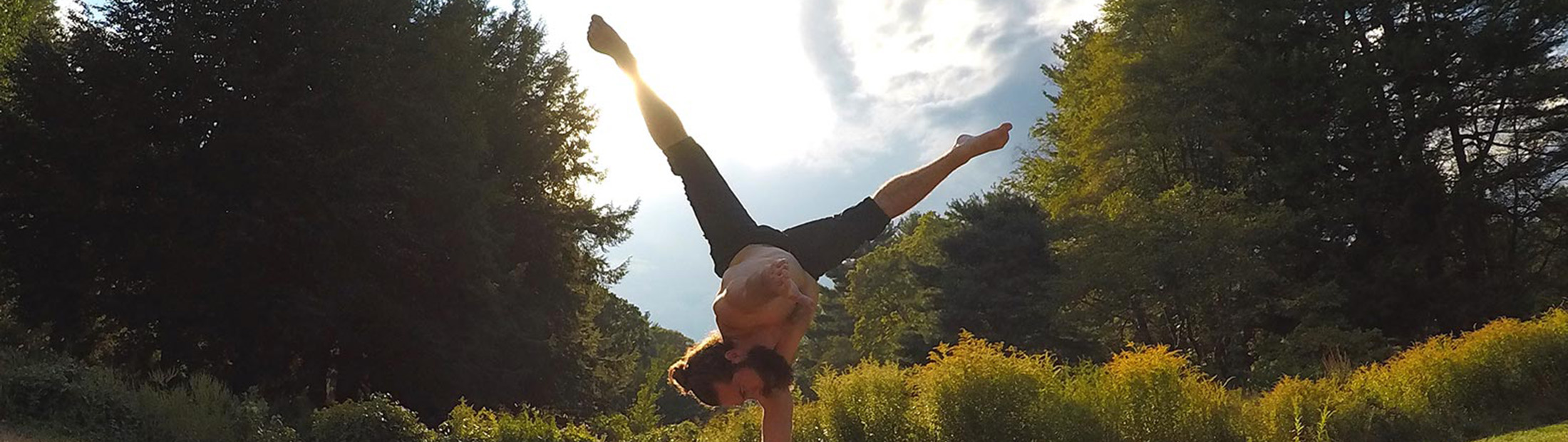 A person doing a one-handed handstand with their legs in a split.