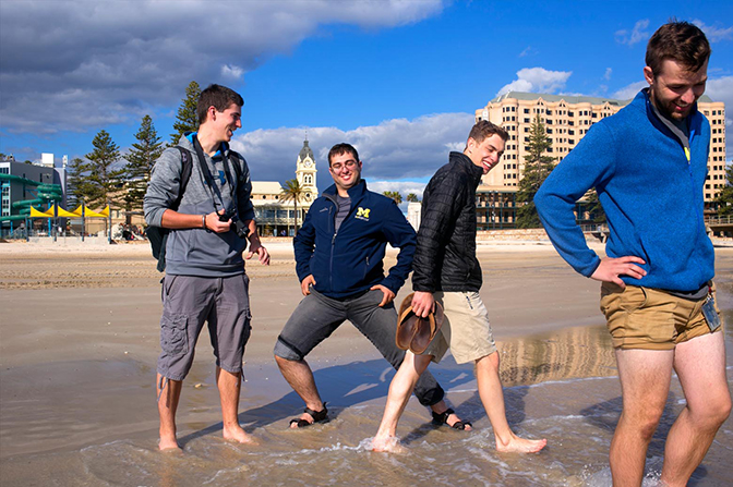 Four students standing on a beach.